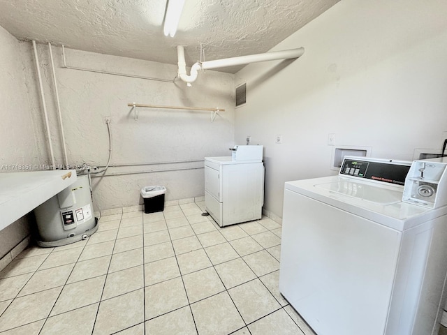 clothes washing area with independent washer and dryer, a textured ceiling, and light tile patterned floors