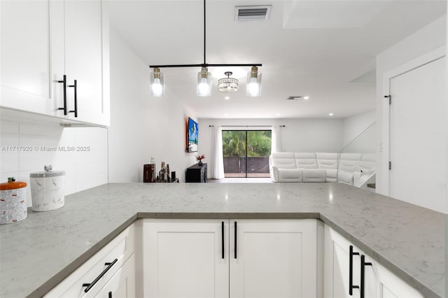 kitchen with decorative backsplash, white cabinetry, and light stone counters