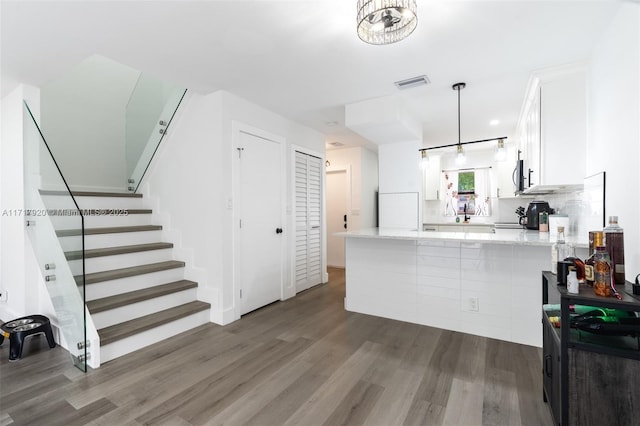 kitchen featuring hanging light fixtures, dark hardwood / wood-style floors, decorative backsplash, white cabinetry, and kitchen peninsula