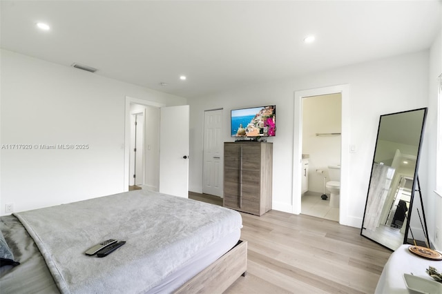 bedroom featuring ensuite bath, a closet, and light hardwood / wood-style flooring