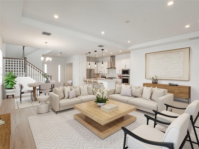 living room with sink, light hardwood / wood-style flooring, and an inviting chandelier