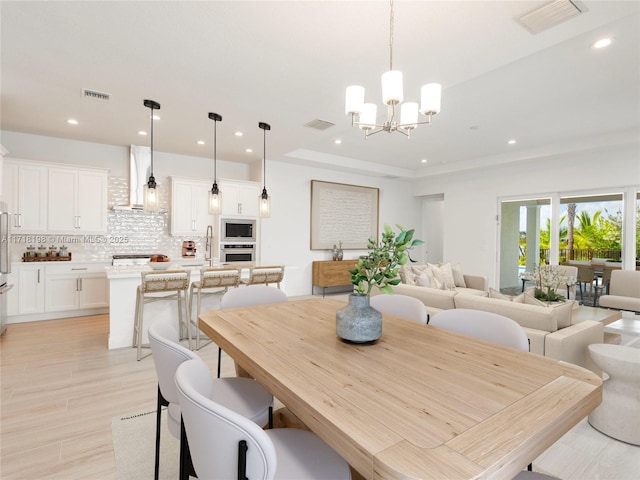 dining room featuring sink, light hardwood / wood-style floors, and a notable chandelier