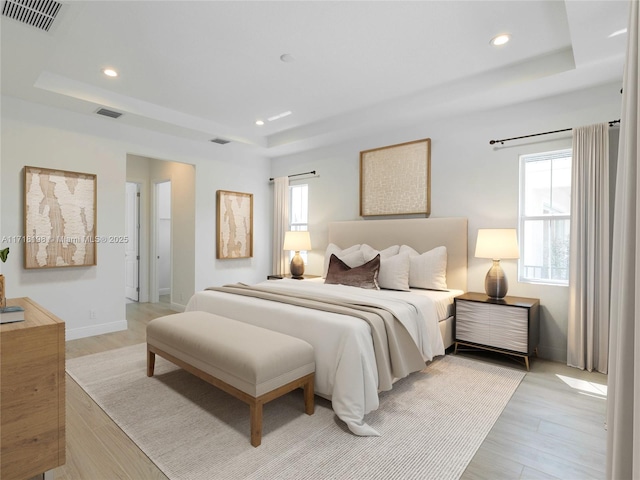 bedroom featuring light hardwood / wood-style floors and a tray ceiling