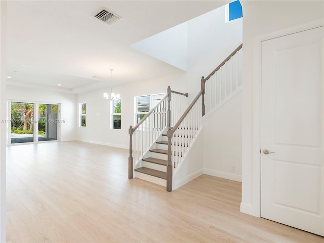 stairway featuring hardwood / wood-style floors, an inviting chandelier, and a raised ceiling