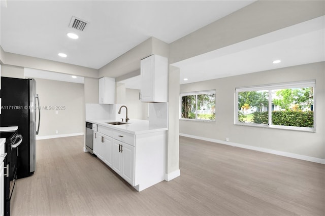 kitchen featuring sink, white cabinetry, light hardwood / wood-style flooring, and stainless steel appliances