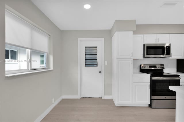 kitchen with white cabinets, light wood-type flooring, and appliances with stainless steel finishes