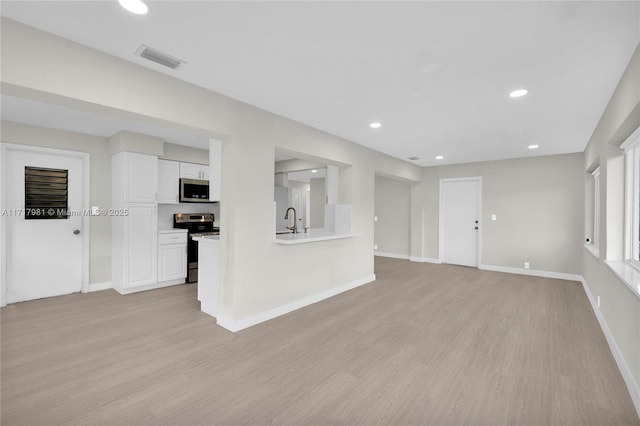 unfurnished living room featuring sink and light wood-type flooring