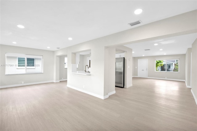 unfurnished living room featuring sink and light wood-type flooring