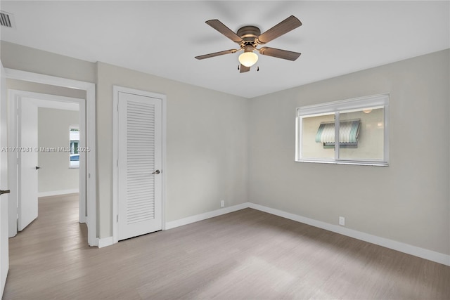 spare room with light wood-type flooring, ceiling fan, and a healthy amount of sunlight