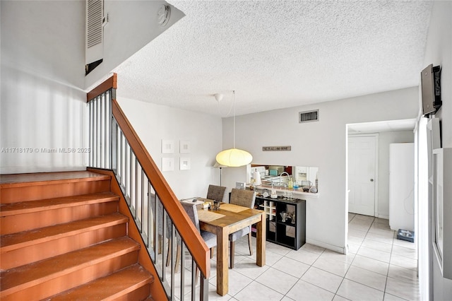 stairs featuring tile patterned flooring and a textured ceiling