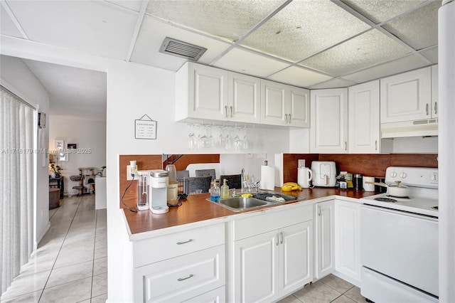 kitchen featuring white cabinetry, a drop ceiling, light tile patterned floors, and white electric stove