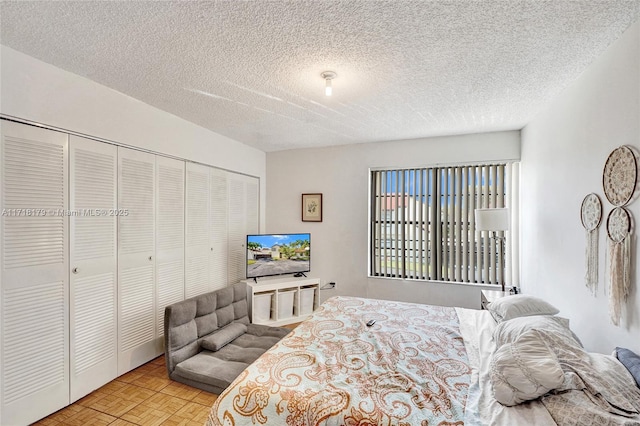 bedroom with a textured ceiling, light parquet flooring, and a closet