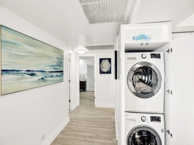 laundry room featuring stacked washer / dryer and light hardwood / wood-style flooring