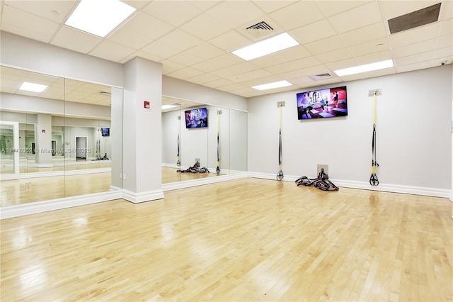 exercise area featuring a paneled ceiling and hardwood / wood-style floors