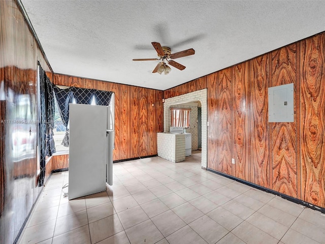 unfurnished room with ceiling fan, wood walls, and electric panel