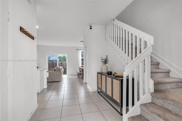 interior space with stairs, light tile patterned flooring, and baseboards