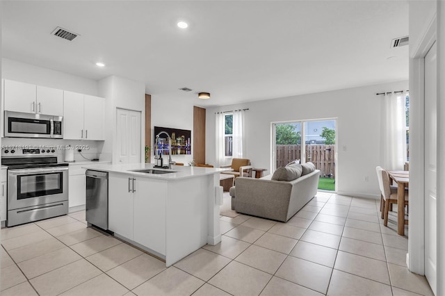 kitchen with a kitchen island with sink, visible vents, open floor plan, light countertops, and appliances with stainless steel finishes