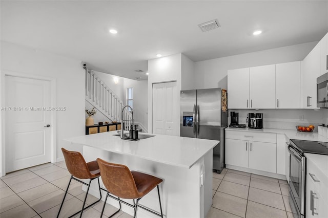 kitchen featuring a sink, visible vents, light countertops, appliances with stainless steel finishes, and an island with sink