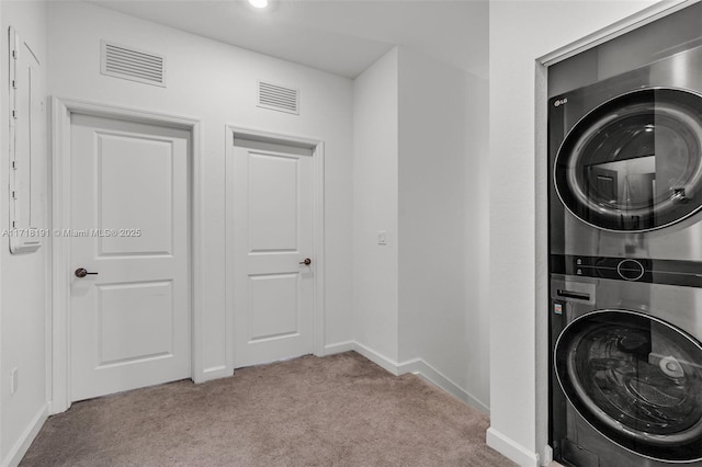 laundry room with light colored carpet, stacked washer / dryer, laundry area, and visible vents