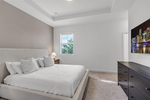 bedroom featuring a raised ceiling, light colored carpet, and baseboards