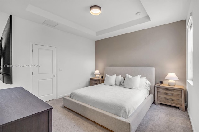 bedroom featuring a tray ceiling, light carpet, and baseboards