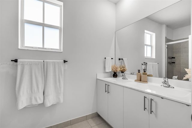 full bath featuring tile patterned flooring, a sink, baseboards, double vanity, and a stall shower