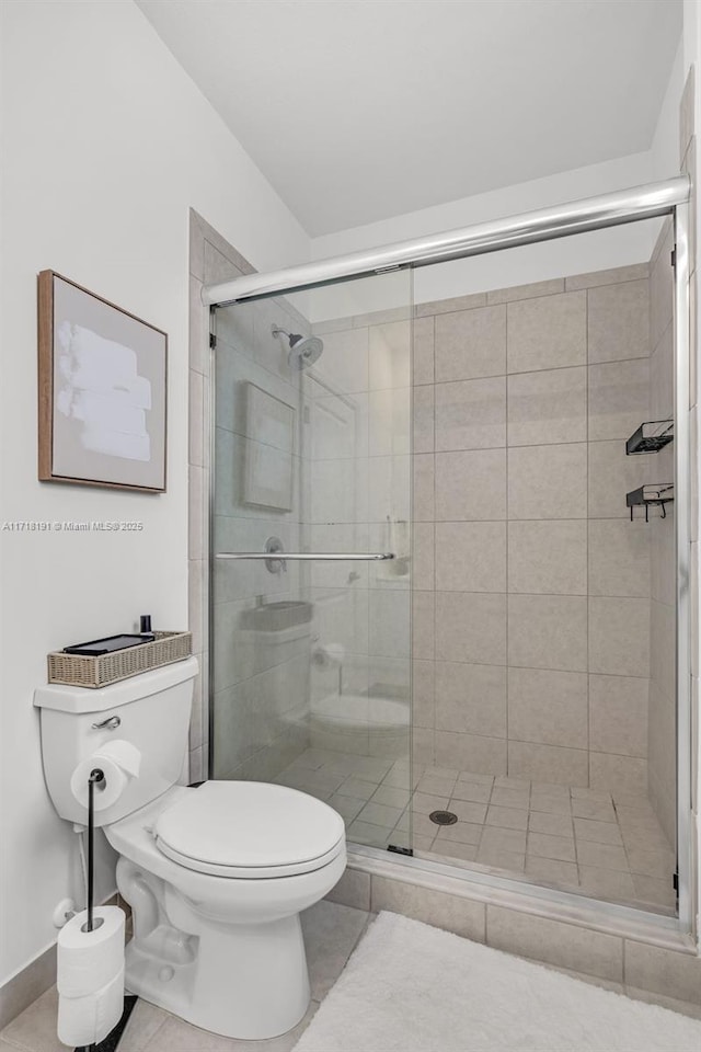 full bath featuring toilet, a stall shower, and tile patterned floors