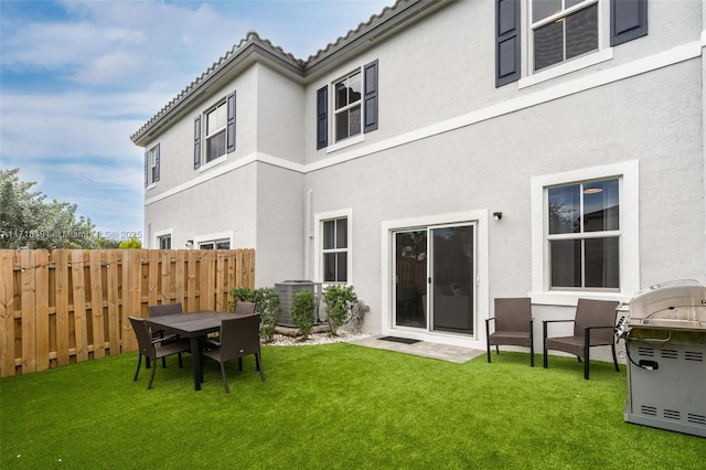 rear view of property with a lawn, fence, and stucco siding