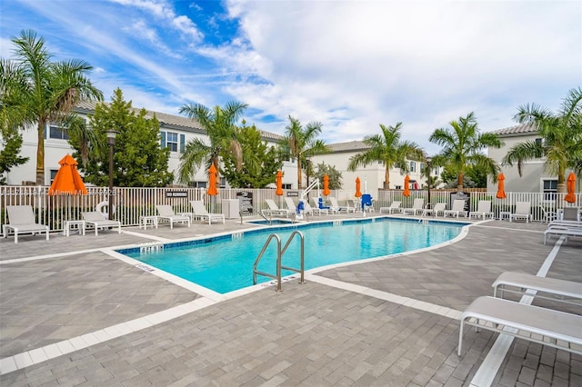 community pool with a patio area and fence