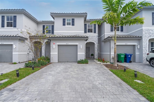 view of front of house with a garage, a tiled roof, decorative driveway, and stucco siding