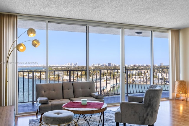 living room with a wealth of natural light, hardwood / wood-style floors, a water view, and a wall of windows