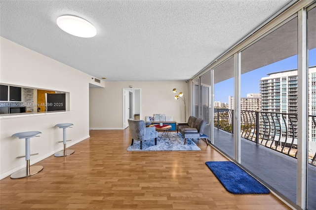 living room with hardwood / wood-style floors, a textured ceiling, and a wall of windows