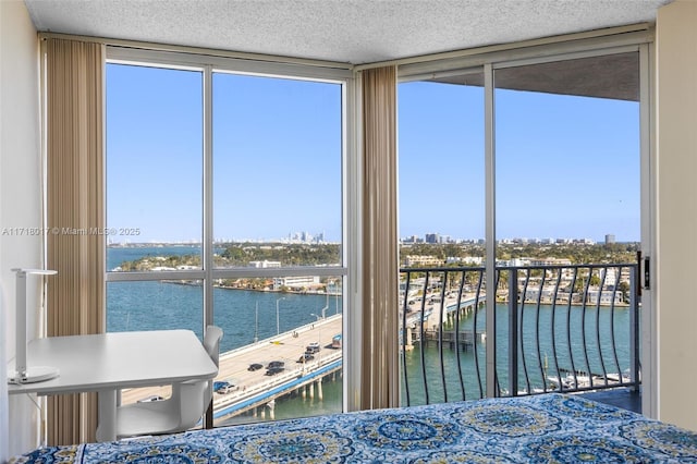 unfurnished bedroom with expansive windows, a water view, and a textured ceiling