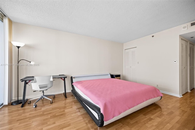 bedroom with a closet, hardwood / wood-style floors, and a textured ceiling