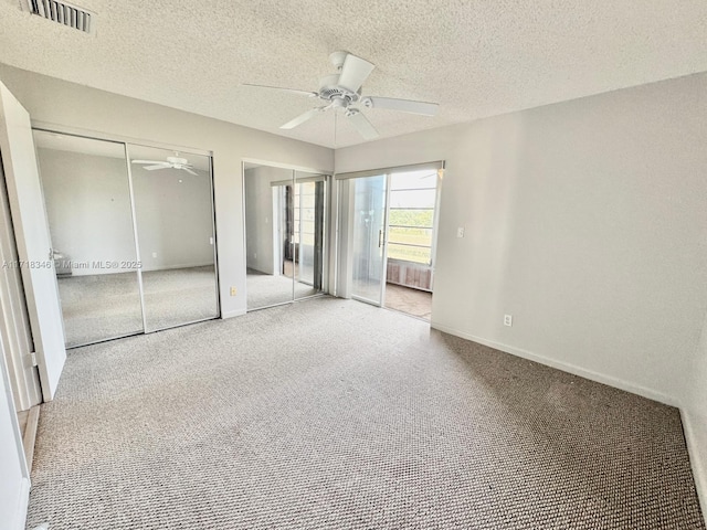 unfurnished bedroom with ceiling fan, carpet floors, a textured ceiling, and two closets