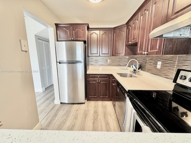 kitchen with backsplash, sink, stainless steel appliances, and light hardwood / wood-style floors