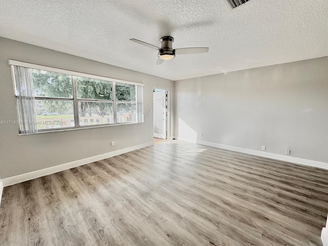 spare room featuring ceiling fan, light hardwood / wood-style floors, and a textured ceiling