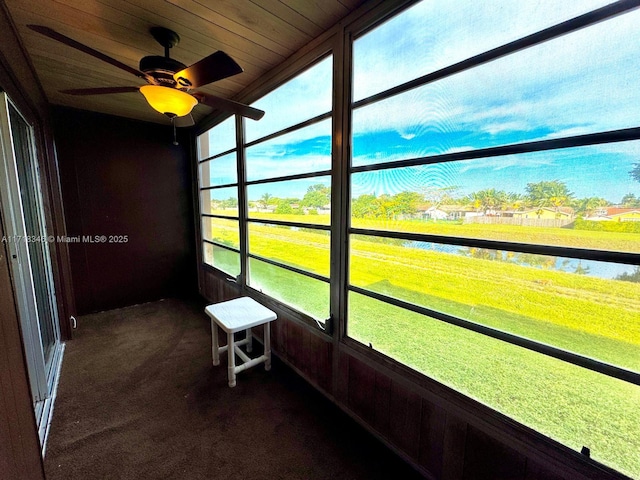 unfurnished sunroom with wooden ceiling, a water view, ceiling fan, and a healthy amount of sunlight