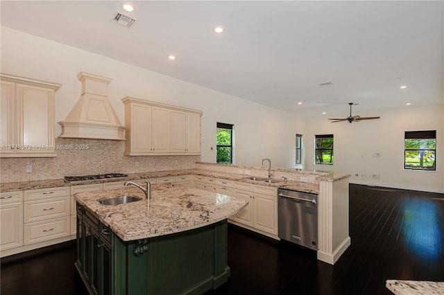 kitchen with ceiling fan, sink, a kitchen island with sink, custom range hood, and appliances with stainless steel finishes