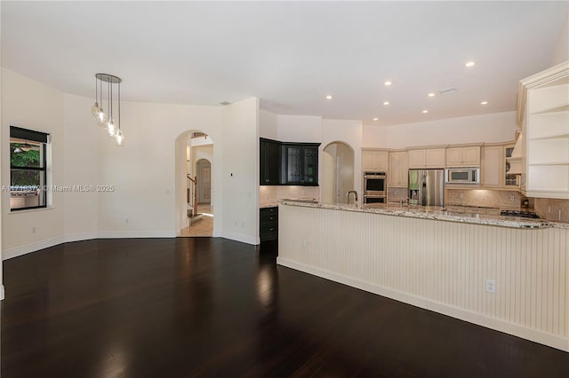 kitchen featuring hanging light fixtures, stainless steel appliances, light stone counters, dark hardwood / wood-style floors, and cream cabinetry