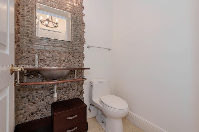 bathroom with toilet, sink, a notable chandelier, and tile patterned flooring