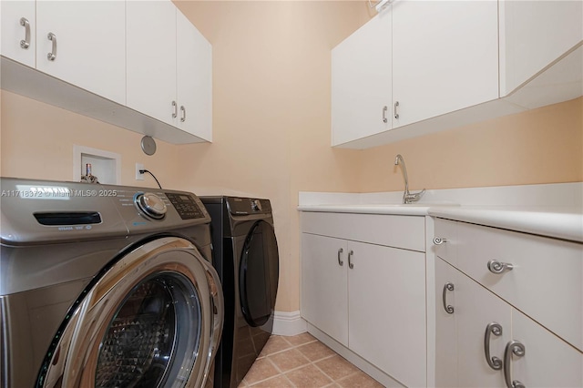 laundry area featuring washing machine and clothes dryer, sink, light tile patterned flooring, and cabinets