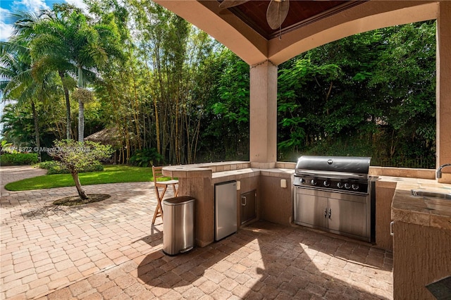 view of patio with an outdoor kitchen, a grill, sink, and ceiling fan