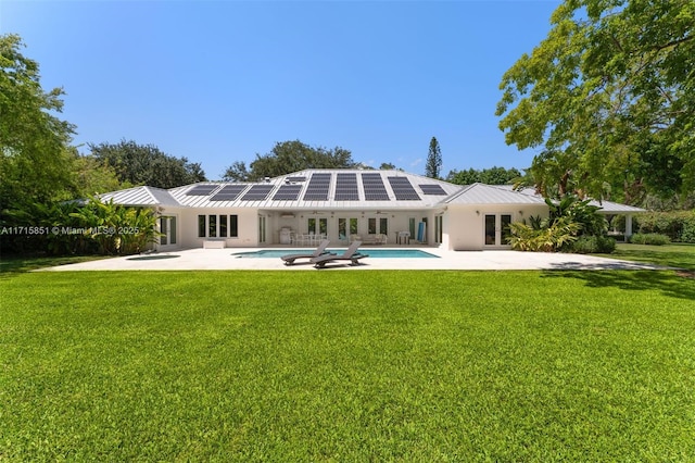 rear view of property with solar panels, a yard, and a patio