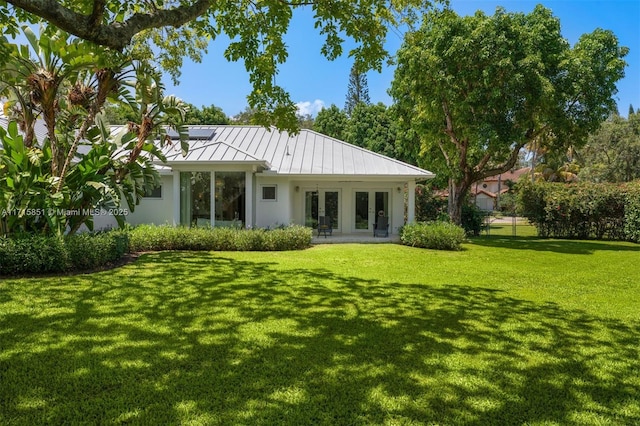 back of property featuring a lawn and french doors