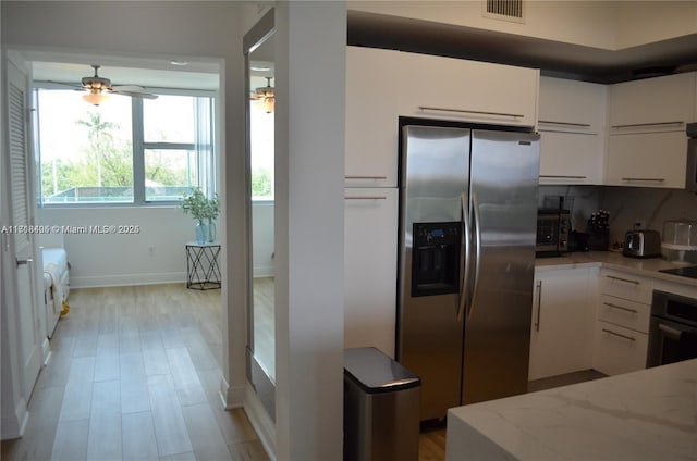 kitchen with ceiling fan, stainless steel refrigerator with ice dispenser, oven, white cabinets, and light wood-type flooring