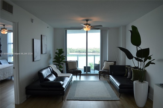 living room featuring ceiling fan, light hardwood / wood-style floors, and a wall of windows