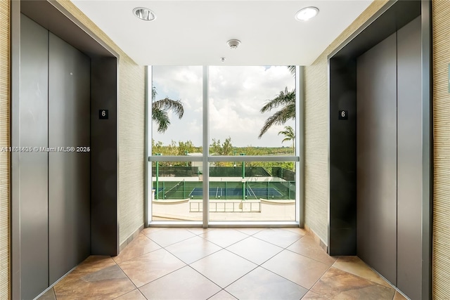 doorway to outside featuring light tile patterned floors, elevator, and expansive windows