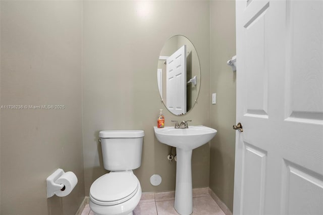 bathroom featuring toilet, tile patterned floors, and sink