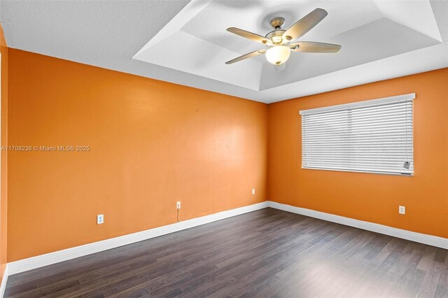 spare room with hardwood / wood-style flooring, a raised ceiling, and ceiling fan